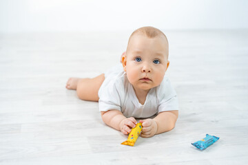 a child on the floor from the studio plays with sweets, crawls, learns the world. cute baby at home. close-up