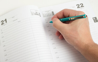 Hand with green ballpoint pen background white notepad sheets.Notes and notes.