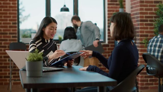 Asian worker greeting female applicant at job interview appointment to discuss work offer and career opportunity. HR recruiter looking at cv and interviewing woman at hiring meeting.