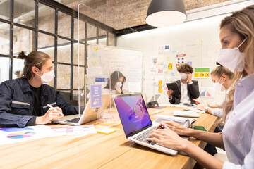 A cheerful young business team, Caucasian and Asian, man and women standing around table, brainstorming about work on table.. Meeting of business partners at the conference.