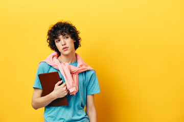 curly guy in a blue T-shirt with a notepad yellow background