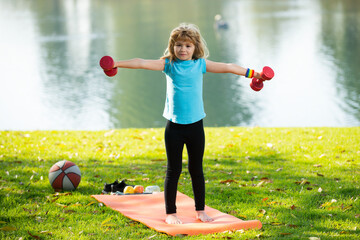 Kids sport. Healthy kid boy with dumbbell exercise outdoor. Little child practice dumbbells...