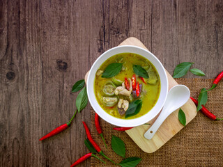 Top view of green curry chicken in white bow on wooden table with copy space