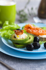 Healthy breakfast. Sandwich with smoked salmon, avocado cheese on lettuce salad leaves and coffee