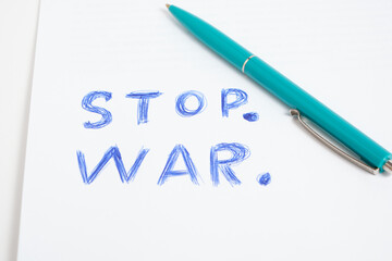 Green ballpoint pen and inscription stop war white sheet.