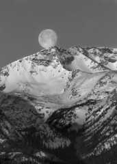 full moon resting at the peak of a mountain