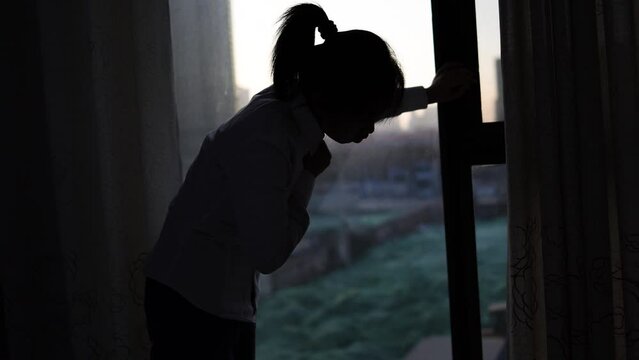 Silhouette of young women with cough and chest tightness in front of the window