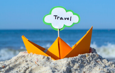 Orange Paper Boat on Sandy Seashore Close-up. Small Boat from Paper on Background of Blue Sea on...