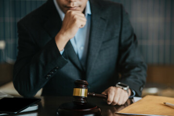 Close up view of auction hammer on the desk in lawyer office and lawyer writing document as courtroom.