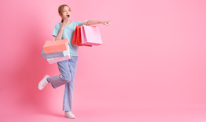 Young Asian woman holding shopping bag on pink background