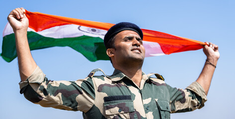 Indian army soldier holding waving Indian flag in uniform - concept national pride, patriotism,...