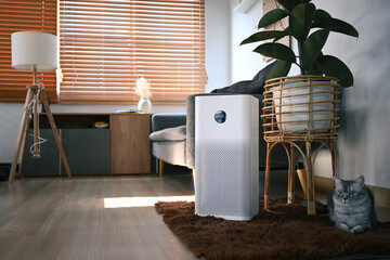 Air purifier with lovely cat and houseplant on wooden floor in living room. Air Pollution Concept.