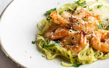 Zucchini pasta with shrimps in a white ceramic bowl , selective focus