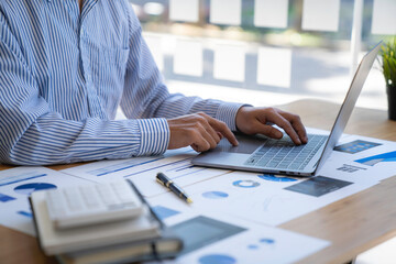 Businessman sitting at desk using laptop and taking notes, analyzing financial data and graphing market growth reports. and investment results, analytical concepts and financial investments.