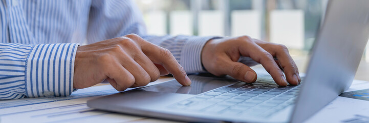 Businessman sitting at desk using laptop and taking notes, analyzing financial data and graphing market growth reports. and investment results, analytical concepts and financial investments.