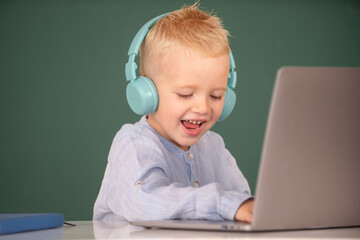 Happy child boy in headphones using a laptop and study online with video call teacher at school. Remote study and education.