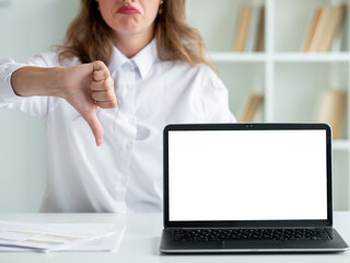 Dislike gesture. Office woman. Computer technology. Unrecognizable displeased lady showing disapproval sign opened laptop blank screen in light room interior defocused.