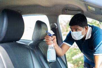 cab or car taxi driver with medical face mask sanitizing passenger seat - concept of coronavirus covi-19 safety measures, hygiene and medical protuction