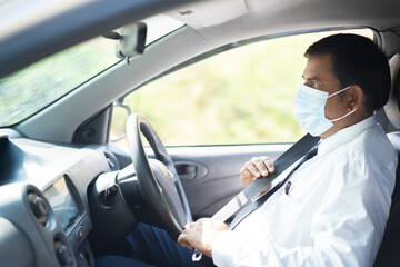 Businessman with medical face mask wearing seat belt before moving car during coronavirus or covid-19 pandemic - concept of safety precautions, pollution and healthcare