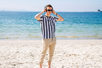 young man on the beach listening to music with headphones