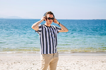 young man on the beach listening to music with headphones