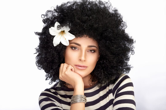 Fashion Model girl with Healthy Curly Afro Hairstyle and Lily Flower in Hair. Beauty portrait on white background with copy space