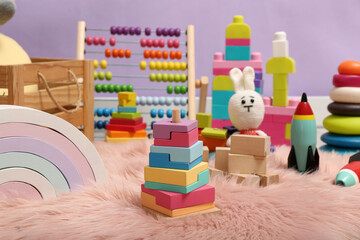 Fototapeta premium Set of different toys on rug near violet wall