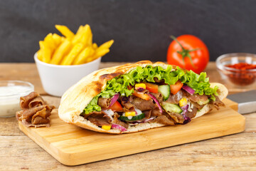 Döner Kebab Doner Kebap slice fast food in flatbread with French Fries on a wooden board
