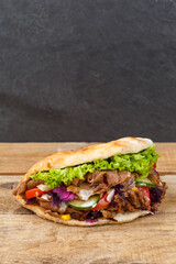 Döner Kebab Doner Kebap fast food in flatbread on a wooden board portrait format