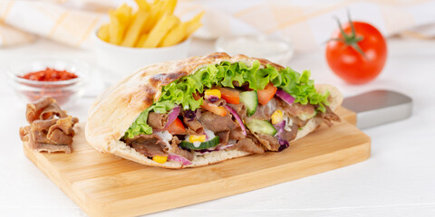Döner Kebab Doner Kebap slice fast food in flatbread with French Fries on a wooden board panorama