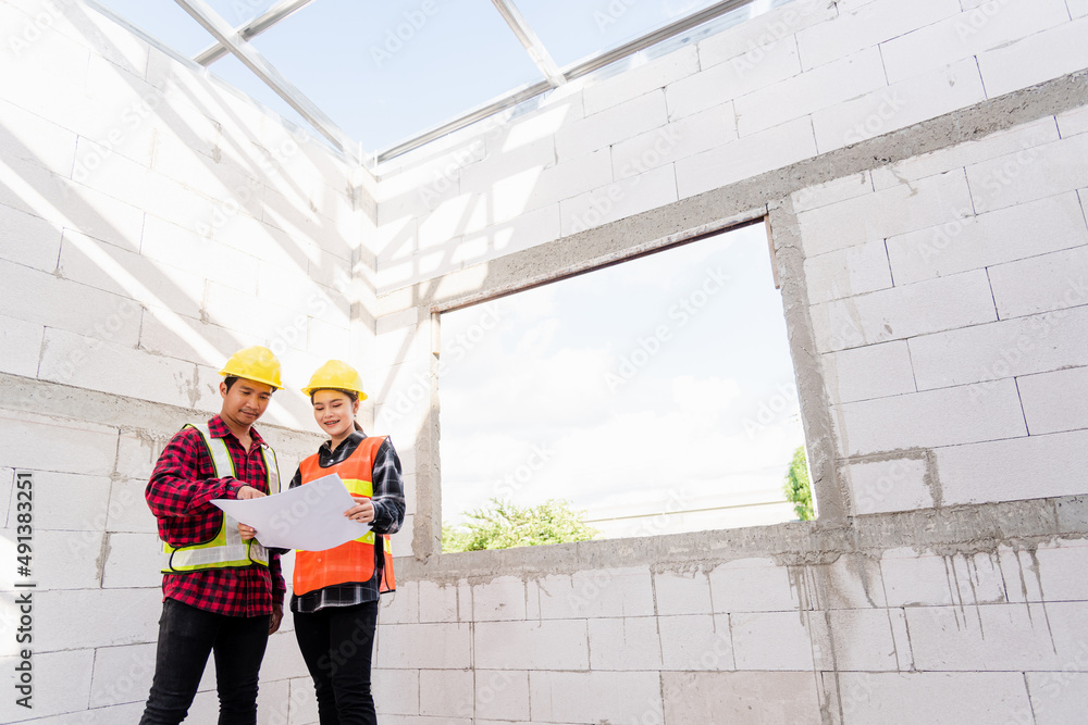 Poster architect and client discussing the plan with blueprint of the building at construction site. asian 
