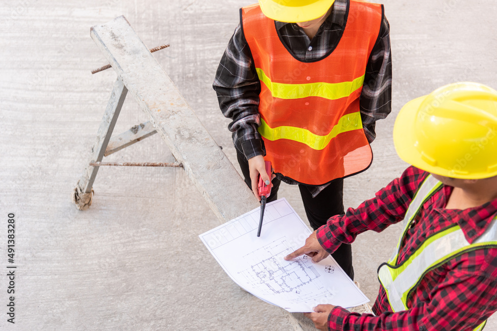 Poster architect and client discussing help create plan with blueprint of the building at construction site