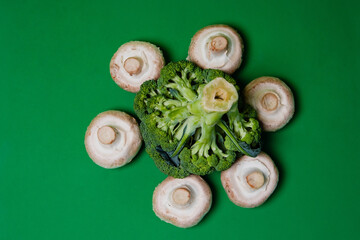 Fototapeta na wymiar Broccoli cabbage and champignon mushrooms on a green background. Useful vegetable.