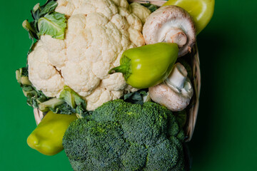 white cauliflower, broccoli and champignons and green peppers on a green background. Vegetarian...