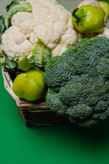 white cauliflower, broccoli and champignons and green peppers on a green background. Vegetarian food.