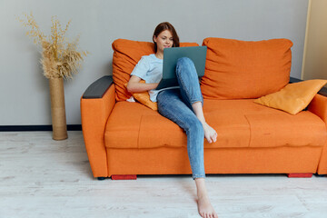 Obraz premium portrait of a woman with long hair lies on the couch with a laptop apartments