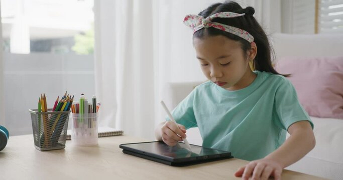 Asia young student Alpha gen Z girl fun play look at touch screen use stylus pen design idea coloring art on home school online class app. Smart kid happy leisure indoor activity sit at table sofa.