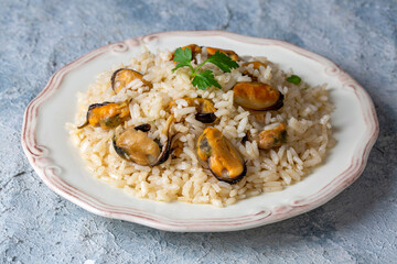 Mussel rice pilaf. Rice with mussels on small white plate on ceramic.