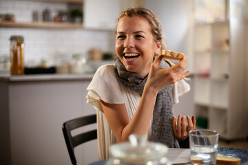 Beautiful woman enjoying in breakfast. Happy young woman eating sandwich at home..