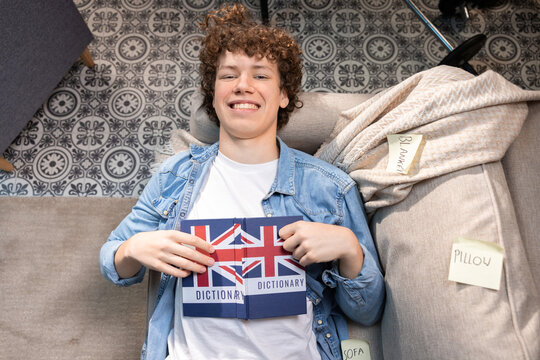 A teenager lies amidst the cards scattered around the room. He is motivated and satisfied with his day.