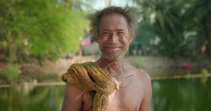 Happy smiling male Asian farmer and mercenary man with beard who is a poor indigenous man would catch fish with nets to feed his livelihood in natural pools.