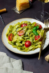 Linguini pasta with pesto sauce, tomatoes and cheese. Healthy eating. Vegetarian food. Italian cuisine.