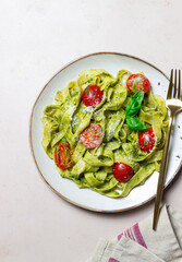 Linguini pasta with pesto sauce, tomatoes and cheese. Healthy eating. Vegetarian food. Italian cuisine.