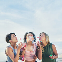 Just be bubbly. Cropped shot of three friends blowing bubbles at the beach.