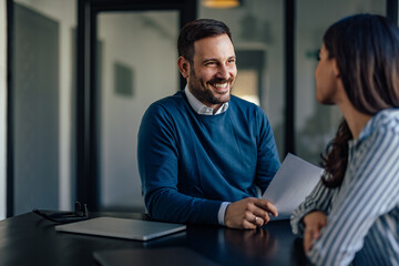 Relaxed business partners, joking around in the office, having fun together.