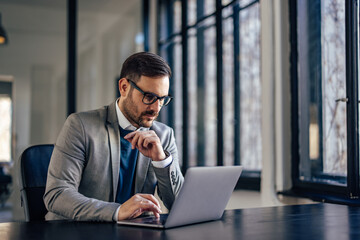 Focused adult caucasian man, completing his work assignments, in the offiec.