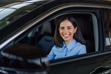 Portrait of a businesswoman, sitting in a car, looking at the ca