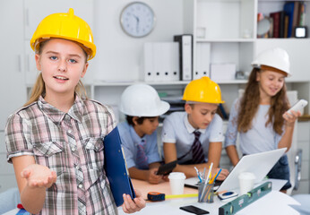 .Portrait of girl in helmet with group of children architects indoors