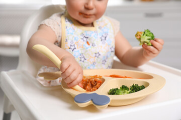 Little baby eating food in high chair, closeup