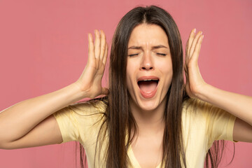 Closeup portrait stressed frustrated woman screaming having temper tantrum isolated on pink...